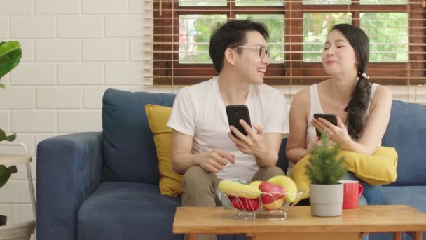 Pasangan bahagia manis menikmati permainan di smartphone bersama-sama ruang tamu latar belakang rumah — Stok Video