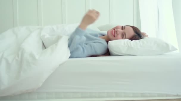 Piękny atrakcyjny Azji kobieta długie włosy uśmiech szczęście relaks rozciąganie po przebudzeniu na biały łóżko sypialnia wnętrze tło — Wideo stockowe