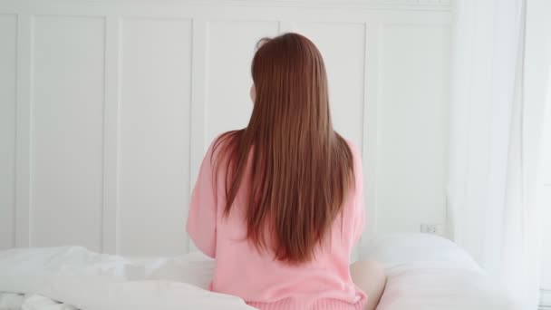 Hermoso largo cabello asiático mujer bonita sonrisa disfrutar smartphone chat después de despertar mañana fin de semana en cama dormitorio interior fondo — Vídeos de Stock