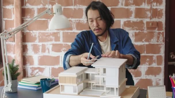 Smart asiático masculino Arquitecto trabajando con su modelo arquitectónico la elección de material y el estudio de la casa modelo de masa ideas de diseño concepto — Vídeos de Stock