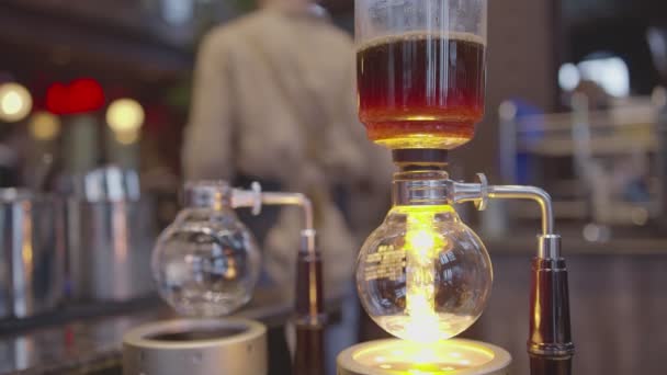 Syphon Koffiezetapparaat op gasfornuis proces wazig koffie shop achtergrond — Stockvideo