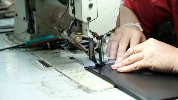 Крупним планом кравець працює над швейною машиною на шкіряному фоні заводу — стокове відео