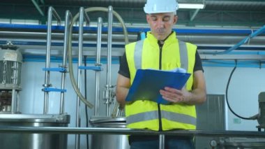 Kafkas erkek kıdemli mühendisler güvenlik üniforması giyiyorlar. Elle kontrol listesi dosya klasörü kalite kontrol makineleri gıda işleme makinesi endüstriyel konseptini kontrol ediyor..