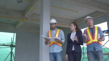 Asyalı genç mühendisler ve bölge müfettişindeki beyaz mühendis meslektaşları inşaat alanındaki dizüstü bilgisayar ve kağıt şablonu kullanarak tartışıyorlar. Ev yenileme fikirleri kavramı