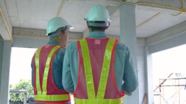 Asyalı genç mühendisler ve bölge müfettişindeki beyaz mühendis meslektaşları inşaat alanındaki dizüstü bilgisayar ve kağıt şablonu kullanarak tartışıyorlar. Ev yenileme fikirleri kavramı