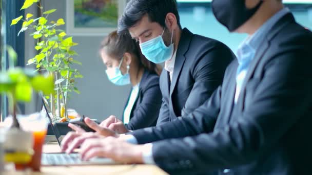 Nuovo concetto di stile di vita normale uomini d'affari che indossano maschera si siedono con distanza sociale di lavoro nell'area pubblica o spazio di co-lavoro con laptop e smartphone — Video Stock