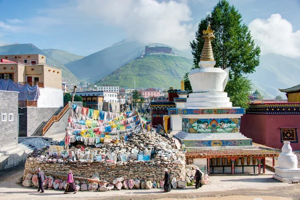 YUSHU (JYEKUNDO), CHINE - 13 juillet 2014 : Des pèlerins tibétains encerclent la pagode. Les dévots marchent 3 fois autour de la pagode et de la pierre de Mani pour accumuler le karma (mérite religieux ). — Photo