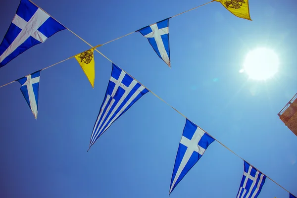 Steaguri grecești triunghiulare pe cer albastru și soare — Fotografie, imagine de stoc