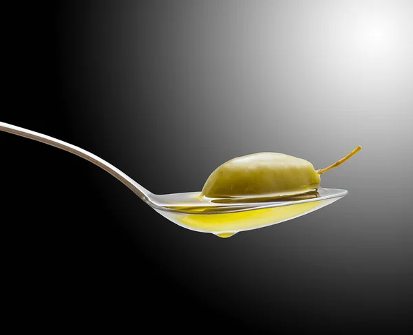 Green olive in full oil spoon on black — Stock Photo, Image