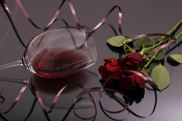 Bouquet of roses and glass red wine on black — Stock Photo, Image