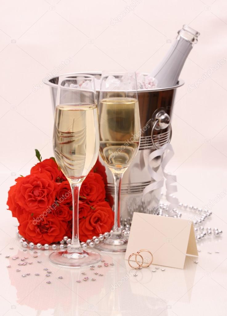 Two champagne glasses, red roses. golden wedding rings — Stockfoto