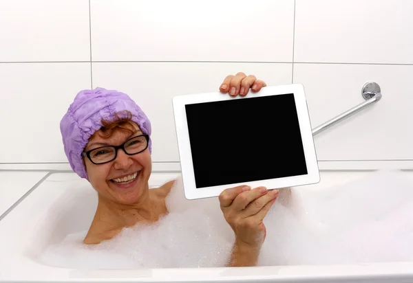 Entusiasta donna matura nella vasca da bagno con tablet — Foto Stock