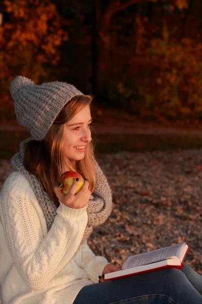 快乐的女孩坐书与苹果在日落 — 图库照片