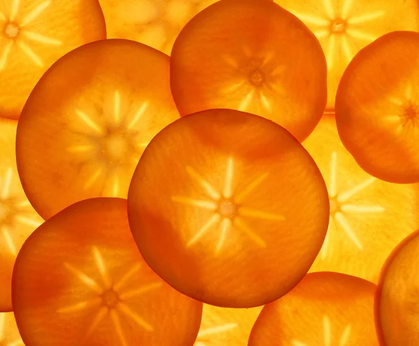 Спелые фруктовые ломтики апельсиновой хурмы в качестве фона для еды — стоковое фото