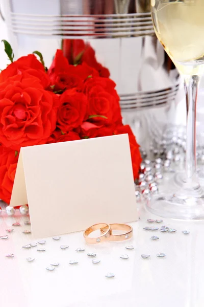 Two golden wedding rings with card, champagne glasses — Stock Photo, Image