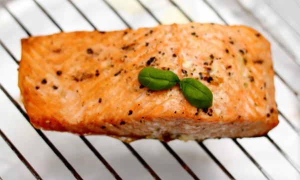 Grilled salmon fillet with basil on grill, soft focus — Stock Photo, Image