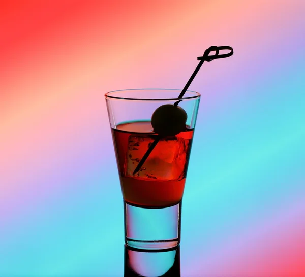 Short drink glass with red liquid and green olive — Stock Photo, Image