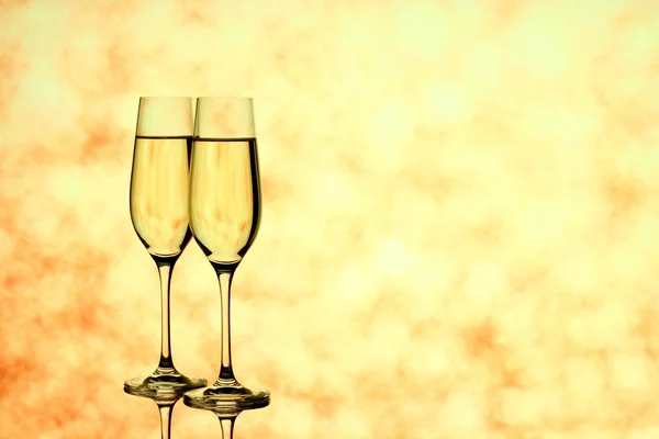 Dois copos de champanhe no fundo dourado borrado — Fotografia de Stock