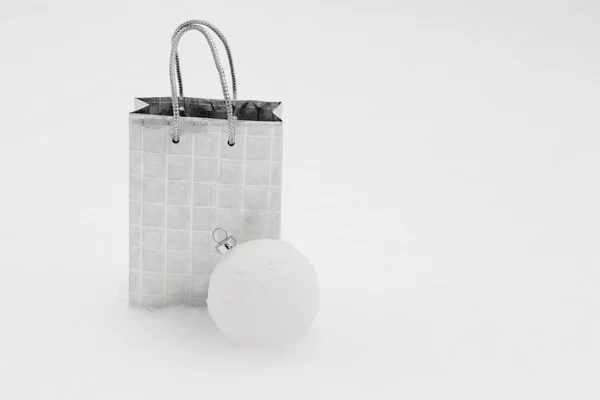 Silver gift bag with Christmas ball in snow — Stock Photo, Image