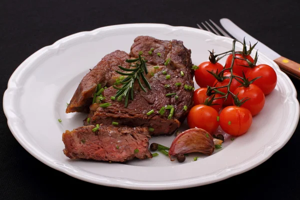 Rib eye stek, pomidory, czosnek, zioła — Zdjęcie stockowe