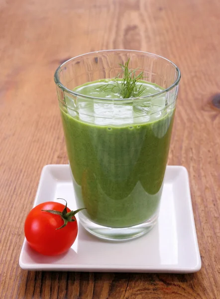 Green spinach smoothie with small red tomato — Stock Photo, Image