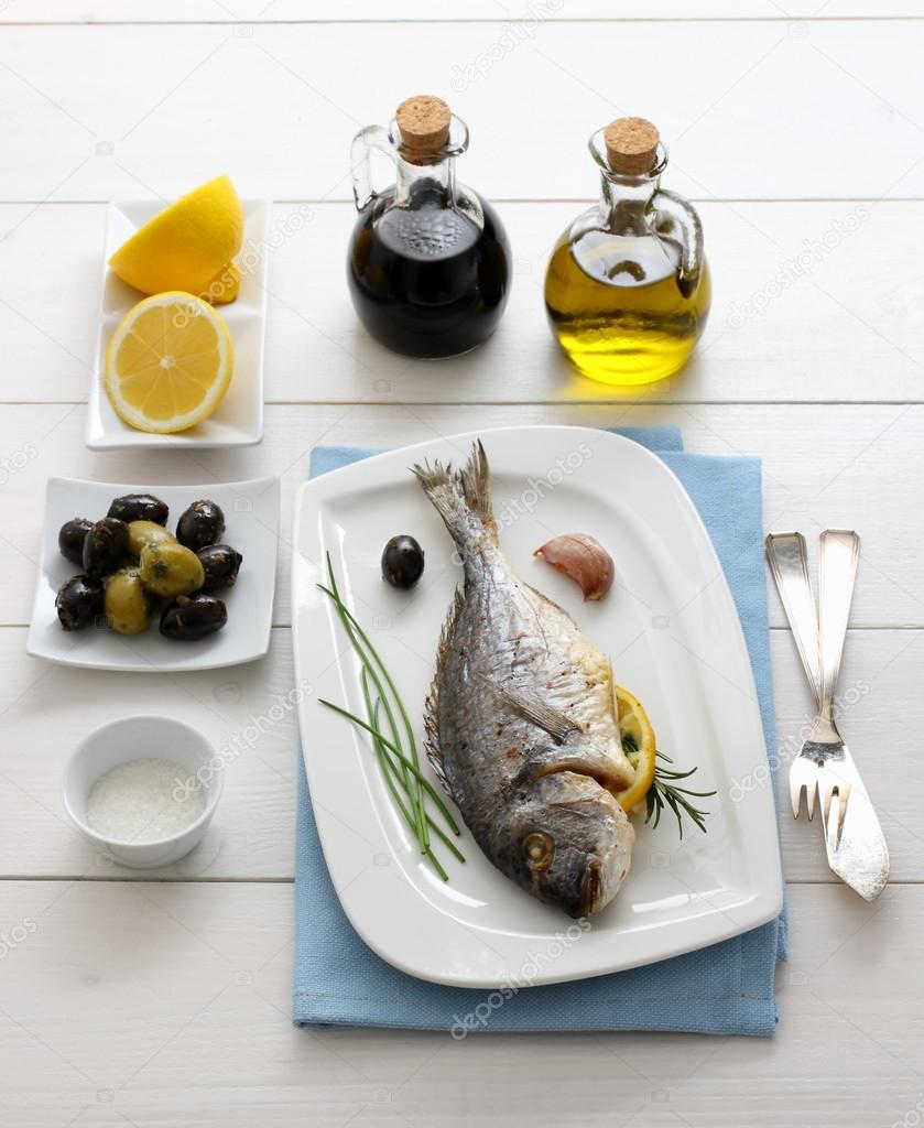 Garnished grilled sea bream with olives, lemon