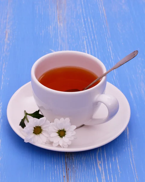 White tea cup and flowers on blue wooden — Stock Photo, Image