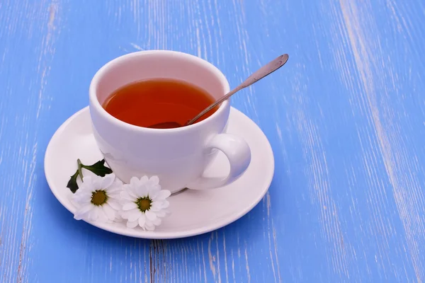 White tea cup and flowers on blue wooden horizontal — Stock Photo, Image