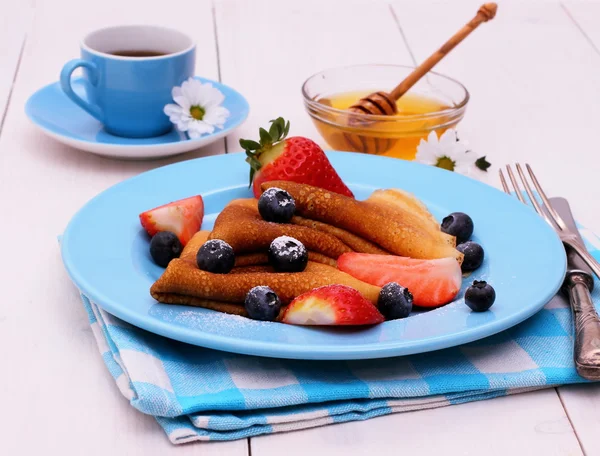 Pfannkuchen und Honiglöffel auf blauem Holz — Stockfoto