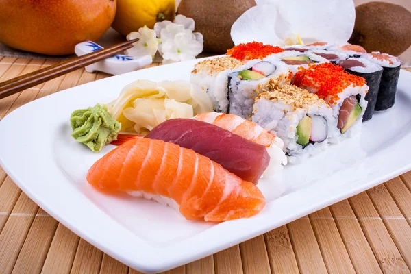 Appetizing sushi with wasabi, fruits and chopsticks — Stock Photo, Image