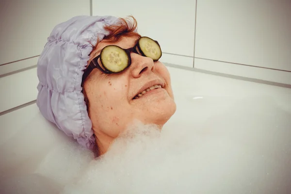 Reife Frau in Badewanne mit Gurkenscheiben auf Gläsern — Stockfoto