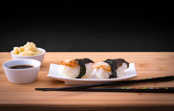 Dos nigiri sushi anguila con salsa de soja en la mesa de bambú —  Fotos de Stock