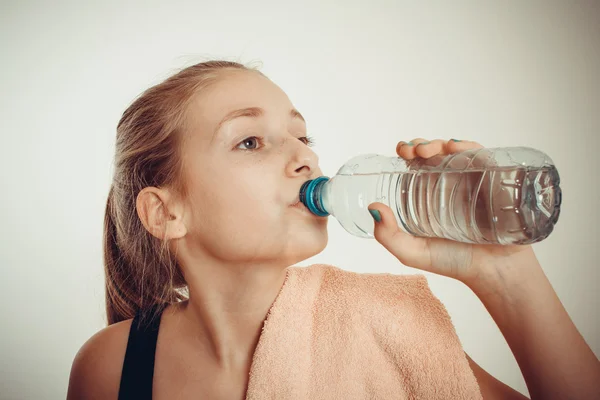 十代の少女は、運動をした後ボトル入りの水を飲む ロイヤリティフリーのストック画像