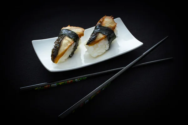 İki nigiri yılan balığı suşi ile çubuk siyah — Stok fotoğraf