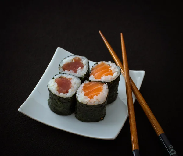 Losos, tuňák maki sushi a hůlky na černém pozadí — Stock fotografie