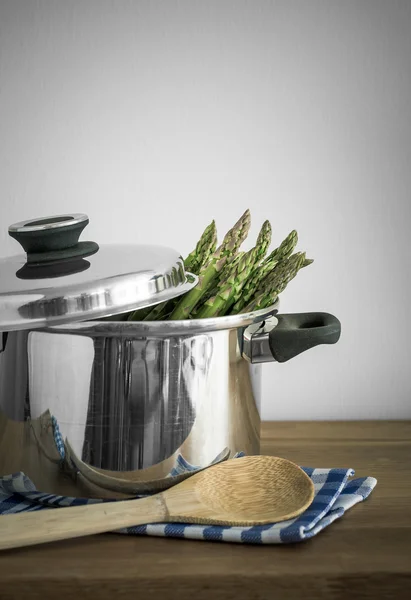 Green asparagus in metal pot with skimmer, selective focus — Stock Photo, Image