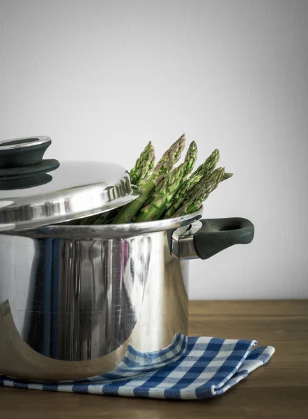 Green asparagus in metal pot with lid, selective focus