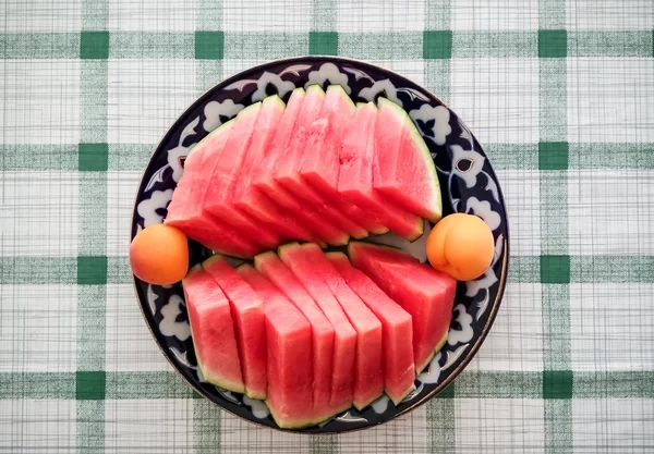 Ripe watermelon with apricots on oriental plate — Stockfoto
