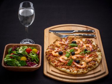 Ton balıklı pizza ile karides ve salata, çatal bıçak takımı