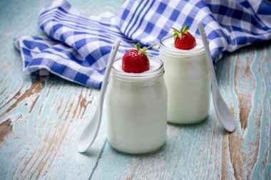 İki yoğurt cam, ahşap plaka üzerinde çilek ile 