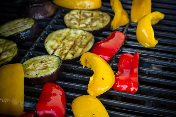 Red and yellow peppers, eggplant slices on grill rack — Stock fotografie