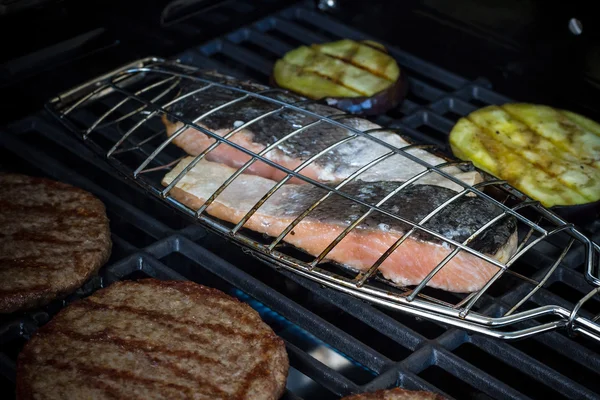 Salmon steak, hamburger slices and eggplant on grill — Stock Photo, Image