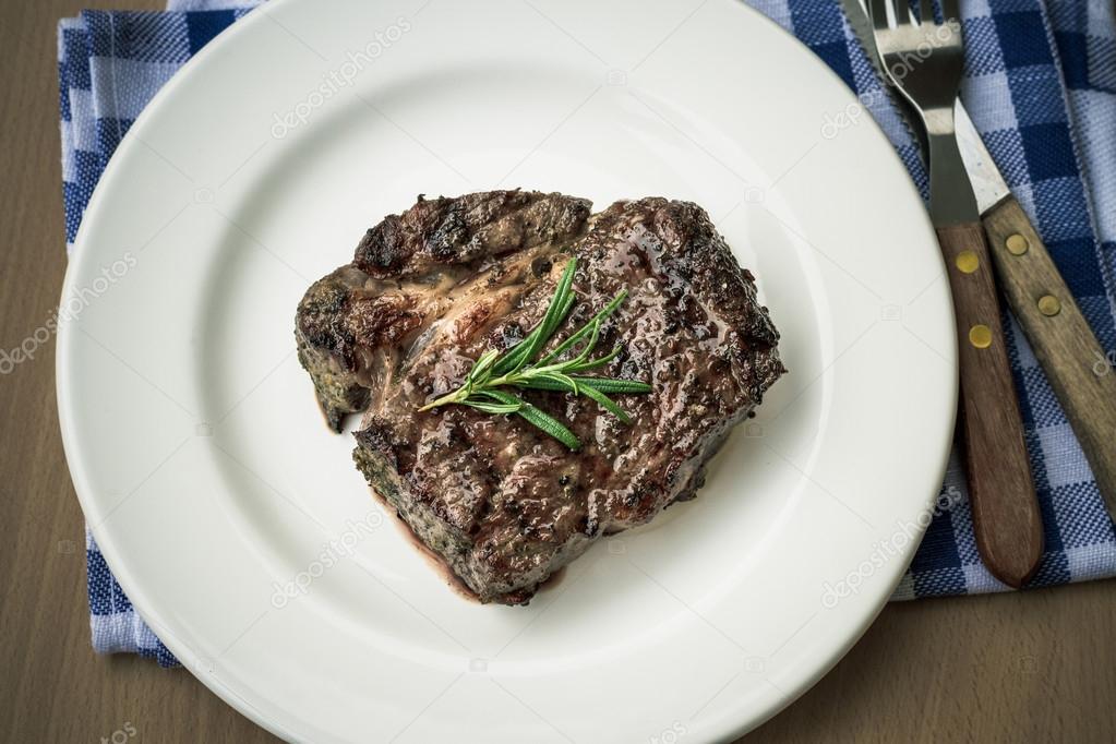 Juicy grilled rib eye steak with cutlery, top view