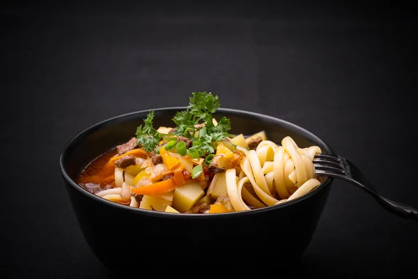 Uzbek noodle soup Lagman on black — Stock Image Uzbek noodle soup Lagman on black Royalty Free Stock Images