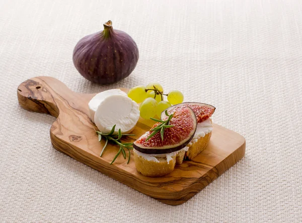 Goat cheese with ripe fig and grapes — Stock Photo, Image