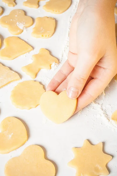 Girl shows heart shape out of dough — Stock Photo, Image