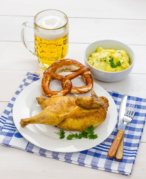 Połowa pieczonego kurczaka, piwo, precel i sałatką ziemniaczaną — Zdjęcie stockowe