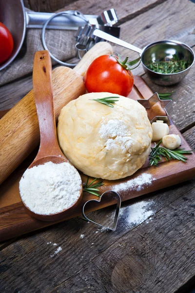 Dough with roller pin and tomatoes — Stock Photo, Image