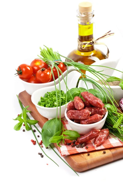 Salsicce con pomodori, verdure e olio d'oliva su una tavola di legno — Foto Stock