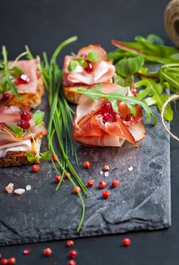 Otlar ve nar taneleri ile dilimlenmiş jambon